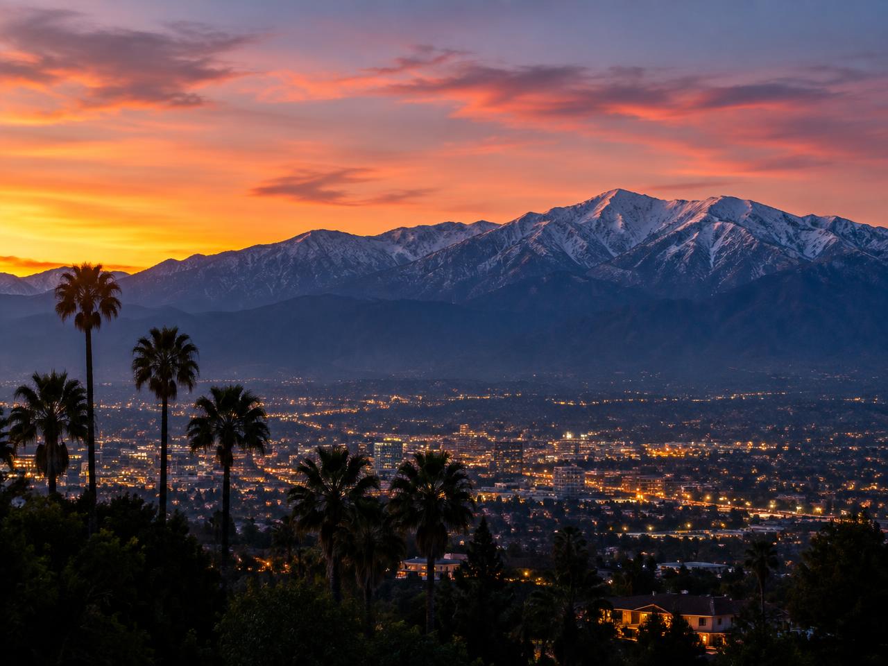 The snow-capped San Gabriel Mountains above the lights of Los Angeles County at sunset